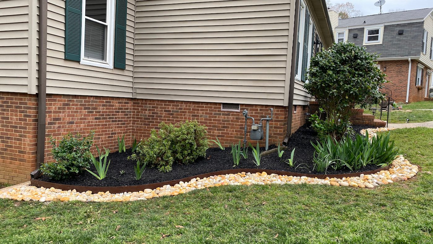 Front bed with fresh mulch, shrubs and stone border by Cifuentes Landscaping